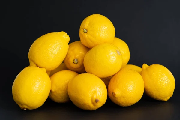 Heap of ripe yellow lemons isolated on black — Photo de stock