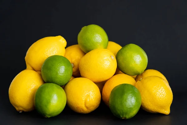 Frische Limetten in Zitronennähe auf schwarzem Hintergrund — Stockfoto