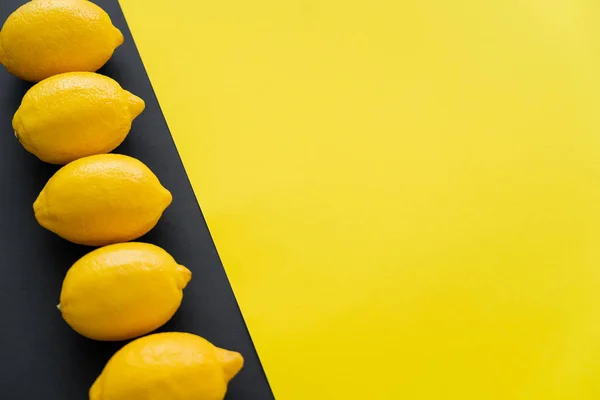 Top view of row of lemons on yellow and black background - foto de stock
