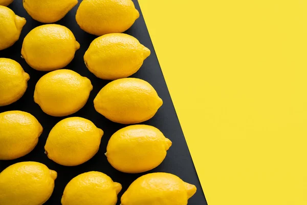 Flat lay with ripe lemons on yellow and black background — Foto stock