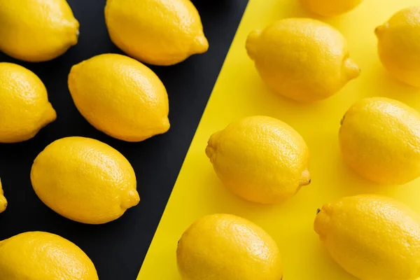 Flat lay with juicy lemons on yellow and black background - foto de stock