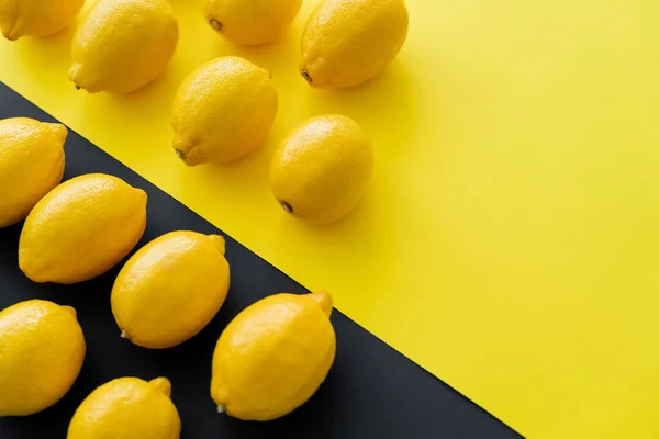 Flache Lage mit hellen Zitronen auf gelbem und schwarzem Hintergrund — Stockfoto