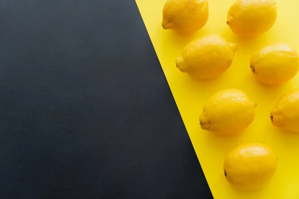 Flat lay com limões frescos em fundo preto e amarelo com espaço de cópia — Fotografia de Stock