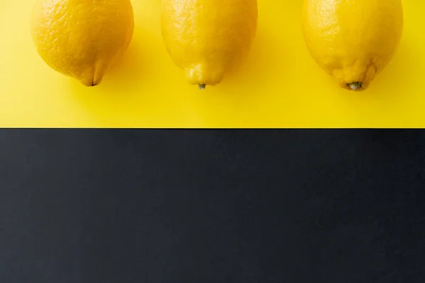 Top view of organic lemons on black and yellow background with copy space — Photo de stock