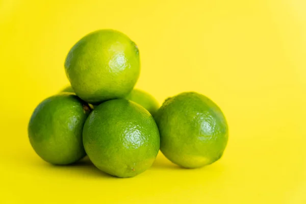Fresh green limes on yellow surface — Stock Photo