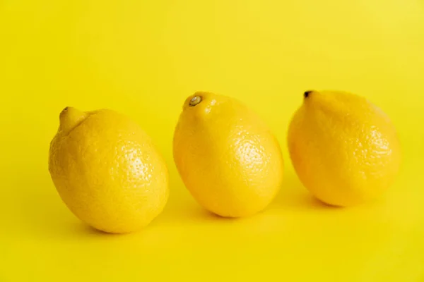 Organic lemons on yellow surface with copy space — стоковое фото