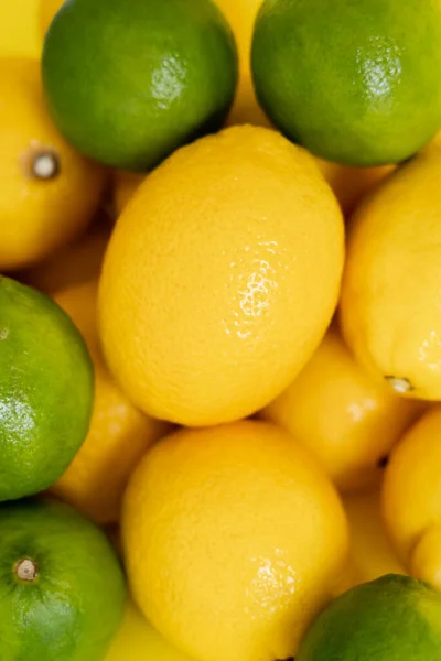 Vista superior de limones orgánicos y limas sobre superficie amarilla - foto de stock