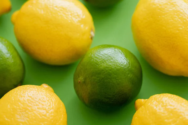 Close up view of ripe lime and lemons on green background — Fotografia de Stock