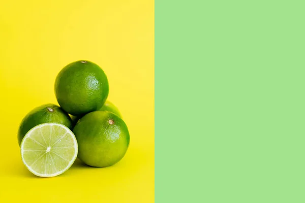 Juicy limes on yellow and green background with copy space — Stockfoto