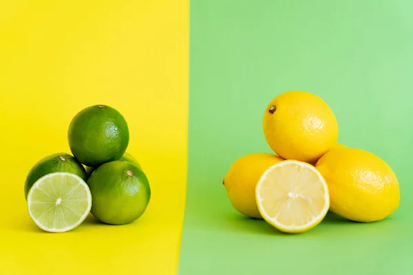 Bio-Zitronen und Limetten mit Hälften auf gelbem und grünem Hintergrund — Stockfoto