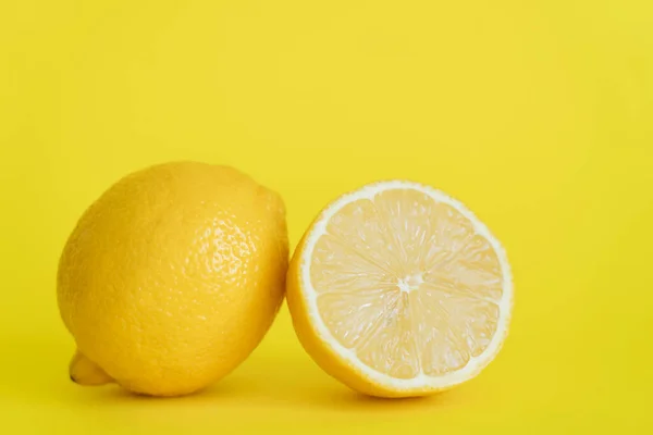 Close up view of half and whole lemon on yellow background — Fotografia de Stock