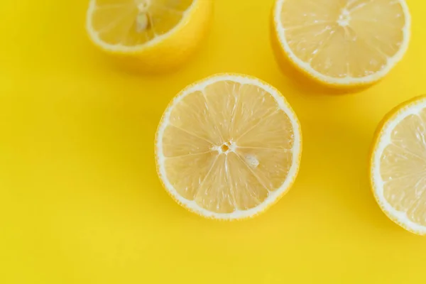 Top view of halves of lemons on yellow background — стоковое фото