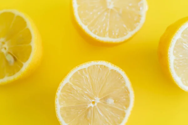 Vista superior de mitades de limones maduros sobre fondo amarillo - foto de stock