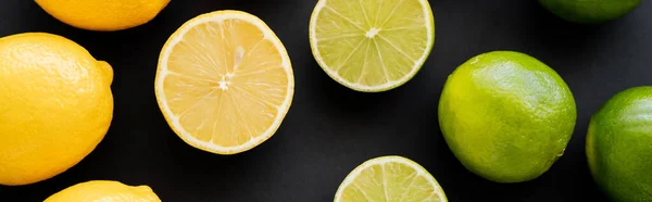 Top view of bright limes and lemons on black background, banner — Stockfoto