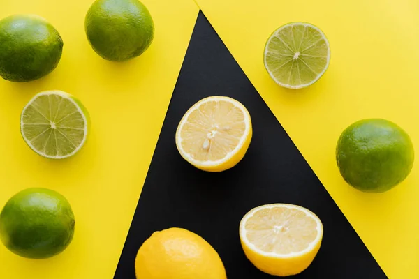 Vue du dessus de limes mûres jaunes et citrons sur fond noir — Photo de stock