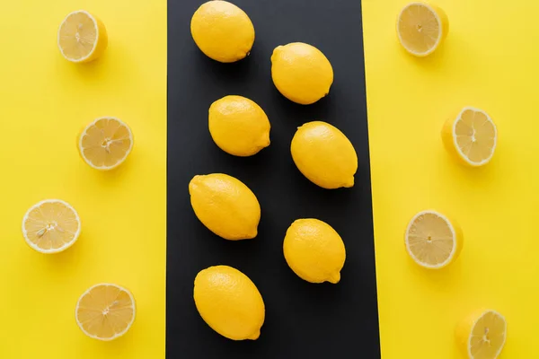 Pose plate avec des citrons entiers mûrs et tasse sur fond noir et jaune — Photo de stock