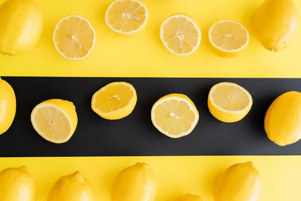 Flat lay of juicy lemons on black and yellow background — стоковое фото