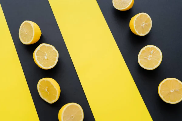 Poser à plat avec des moitiés de citrons sur fond noir et jaune — Photo de stock