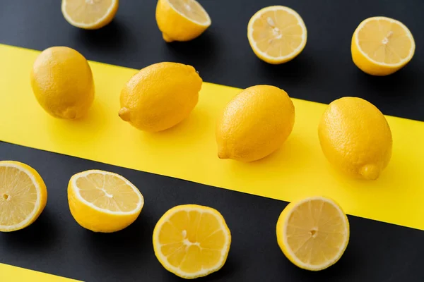 Flat lay of organic lemons on black and yellow background — Stock Photo