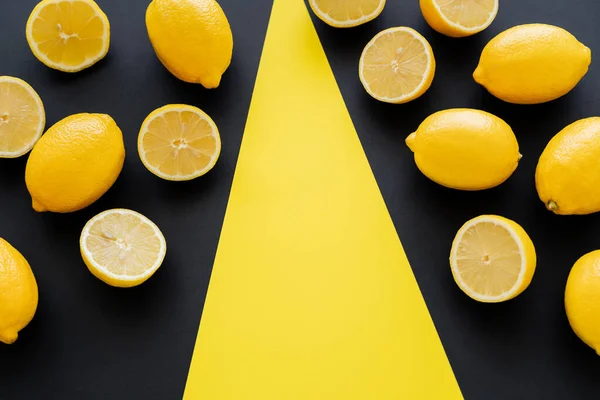 Flat lay with juicy lemons on black and yellow background — Stock Photo