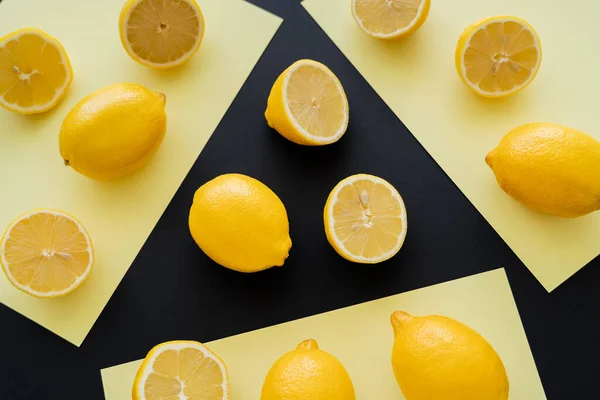 Flat lay with bright lemons on beige and black background — Fotografia de Stock