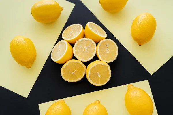 Flat lay with round of cut lemons on beige and black background — Photo de stock