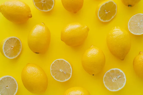 Colocación plana de limones brillantes en la superficie amarilla - foto de stock