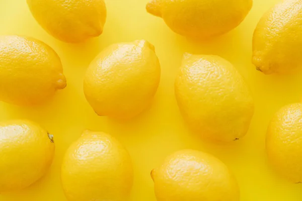 Vista superior de limões maduros na superfície amarela — Fotografia de Stock