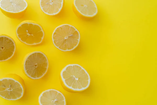 Vista superior de mitades de limones frescos sobre superficie amarilla - foto de stock