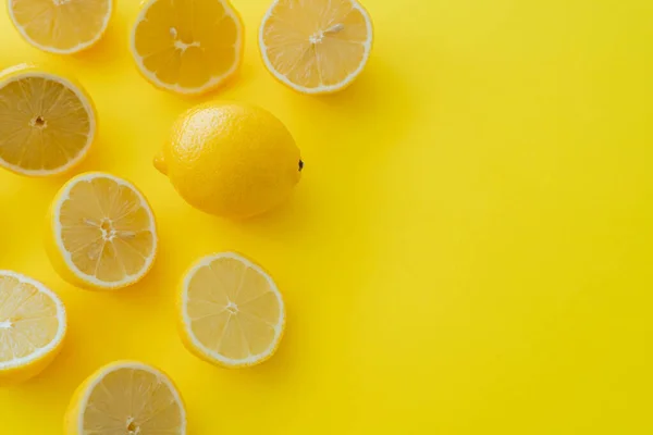 Вид зверху на стиглий лимон біля половинок на жовтій поверхні — стокове фото