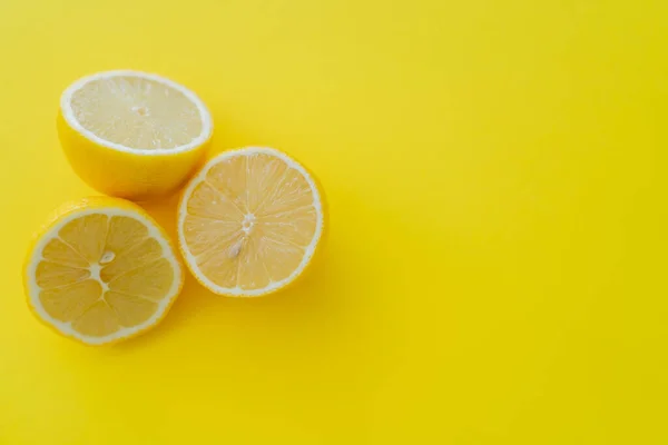 Vista superior de mitades de limones sobre fondo amarillo - foto de stock