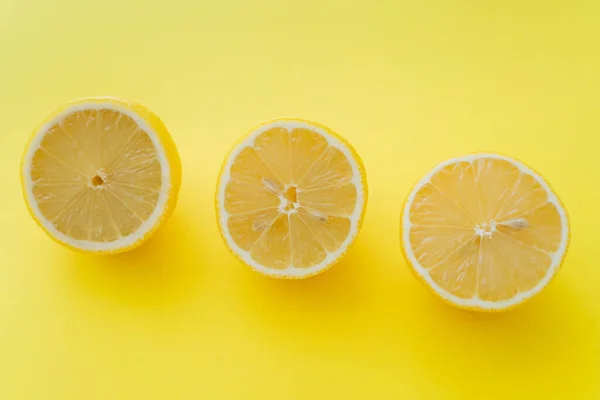 Top view of fresh halves of lemons on yellow surface — Fotografia de Stock