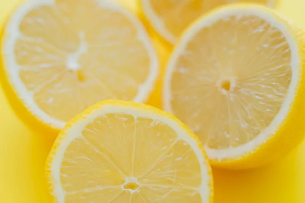 Vista de cerca de mitades borrosas de limones en la superficie amarilla - foto de stock