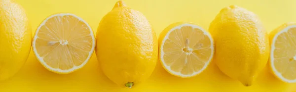 Colocación plana con corte y limones enteros en la superficie amarilla, pancarta - foto de stock