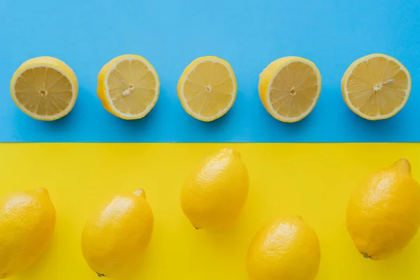 Acostado plano con limones sobre fondo azul y amarillo - foto de stock