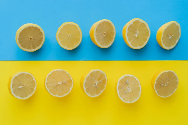 Top view of ripe halves of lemons on blue and yellow background — Stock Photo