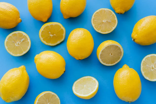 Top view of halves and whole lemons on blue background — стоковое фото