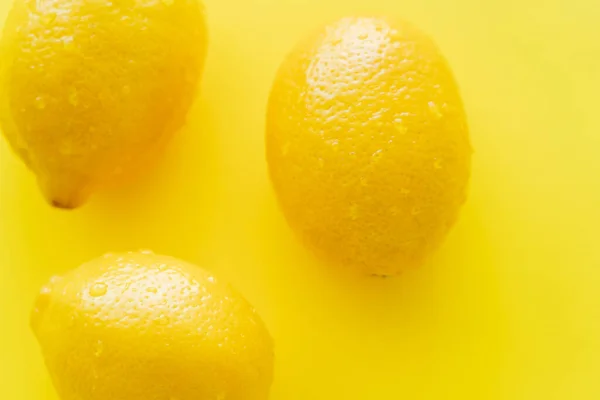Top view of wet lemons on yellow background — Stock Photo
