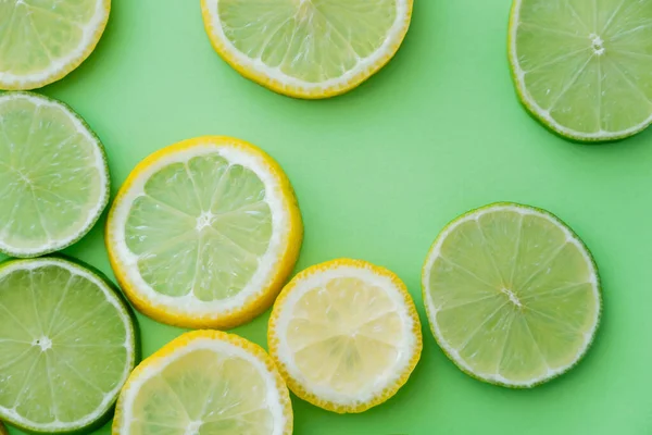 Vista dall'alto di limoni e lime tagliati a fette su sfondo verde — Foto stock