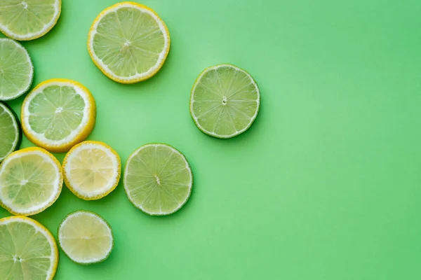 Top view of sliced fresh lemons and limes on green background with copy space — Fotografia de Stock