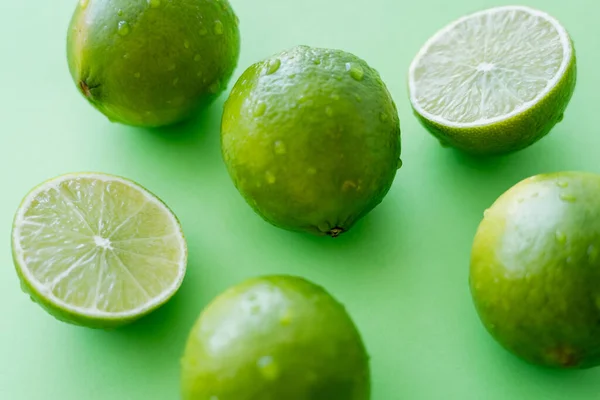 Close up view of ripe limes with water drops on green background — Stockfoto