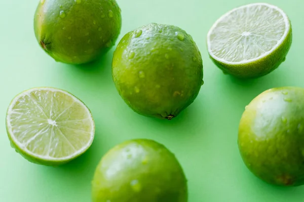 Vista ravvicinata di lime mature con gocce d'acqua su fondo verde — Foto stock