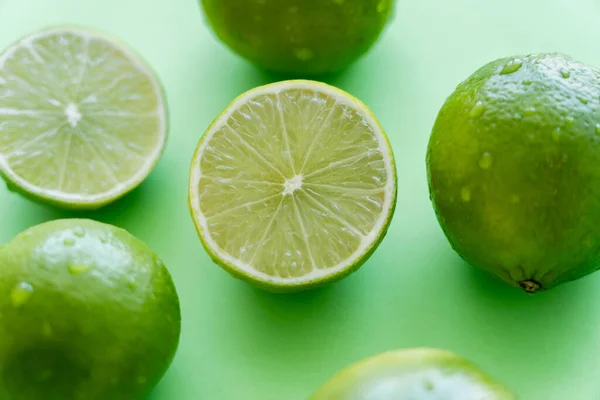 Vista de cerca de jugosas limas con gotas de agua sobre fondo verde - foto de stock