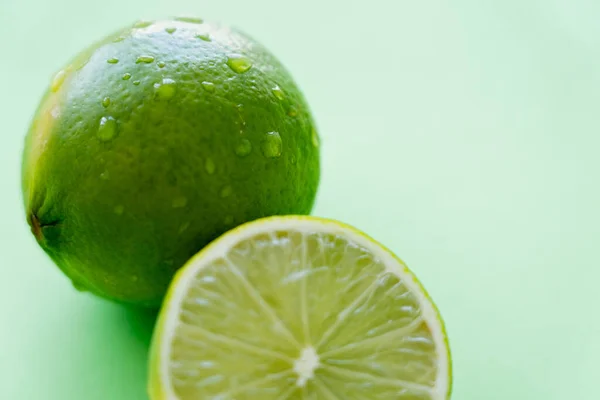 Close up view of fresh lime with water drops on peel on green background — Fotografia de Stock