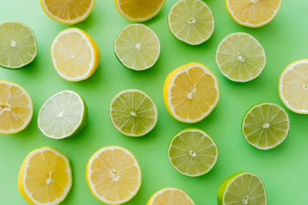 Top view of cut limes and lemons on green background — стоковое фото