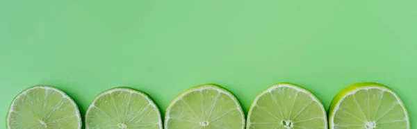 Top view of sliced lime on green background, banner — Stock Photo