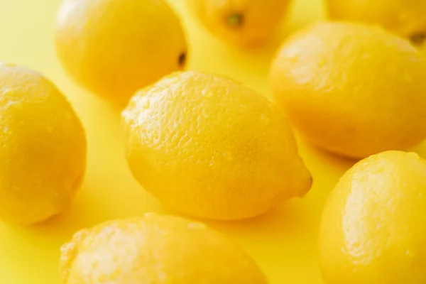 Vista de cerca de limones húmedos en la superficie amarilla - foto de stock