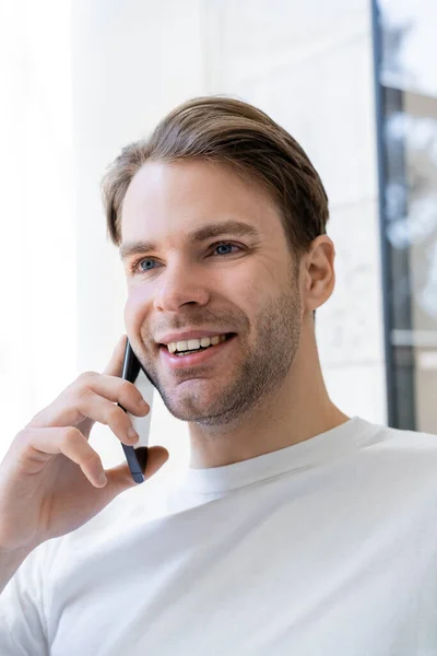 Retrato del joven sonriendo durante la conversación en el teléfono móvil - foto de stock
