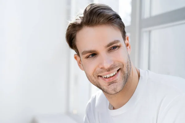 Porträt eines positiven Mannes, der zu Hause wegschaut und lächelt — Stockfoto