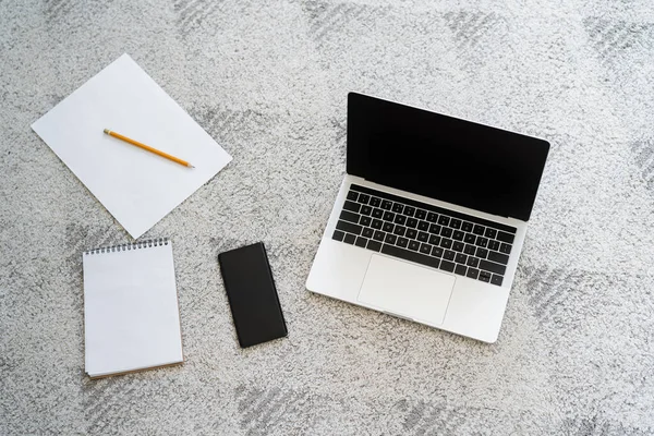 Vista superior do laptop e smartphone com tela em branco perto de papel e notebook no tapete cinza — Fotografia de Stock